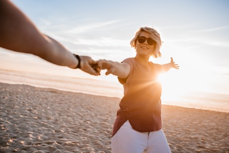 Smiling woman walking with her girlfriend along a sandy beachの写真素材