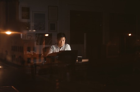 Young Asian businessman working overtime alone in a dark officeの素材 [FY310111147709]