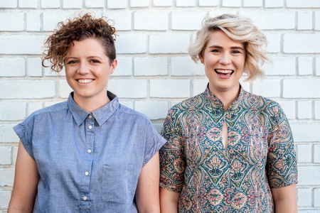 Laughing young lesbian couple standing together outsideの写真素材