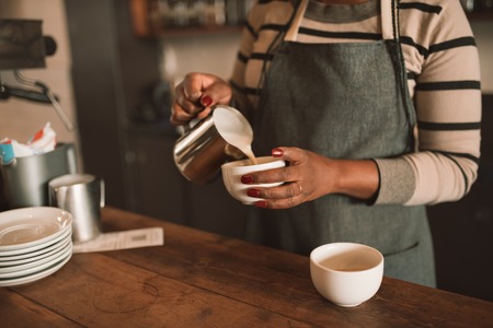 Closeup of an African barista making a cup of cappuccinoの写真素材