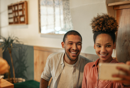Smiling young couple sitting in a bar taking selfies together