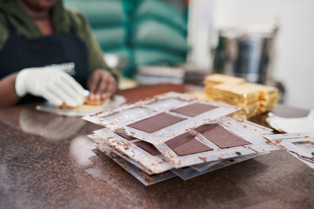 Worker packaging chocolate bars from molds in gold foilの写真素材