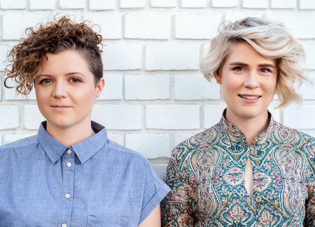 Smiling young lesbian couple standing together outsideの写真素材