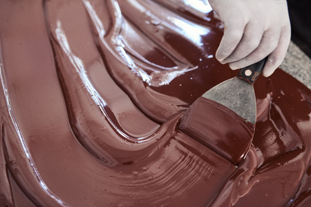 Worker using a spatula to mix chocolate on a tableの写真素材