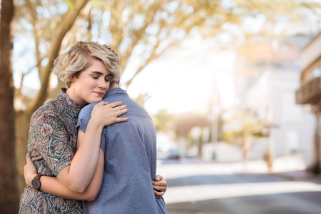 Loving young lesbian couple standing outside hugging each otherの写真素材