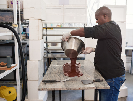 Worker pouring melted artisanal chocolate out on a factory tableの写真素材