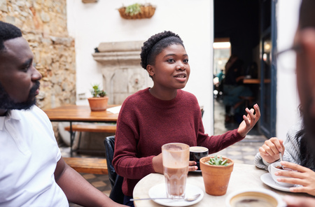 Young woman talking with friends in a trendy cafe courtyardの写真素材