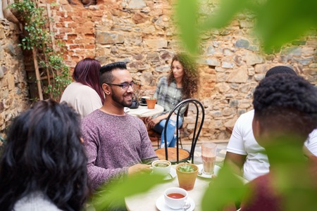 Friends chatting together over coffee in a trendy cafe courtyardの写真素材