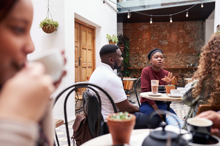 People talking together over coffee in a trendy cafe courtyardの写真素材