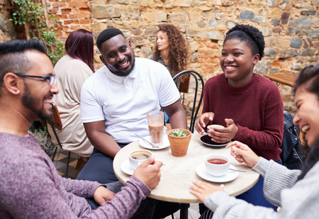 Friends talking over coffee in a trendy cafe courtyardの写真素材