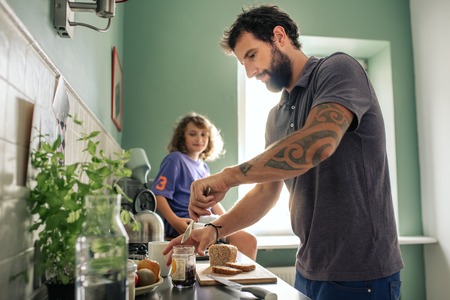 Young boy watching his father make sandwiches in their kitchenの写真素材