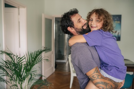 Smiling boy being held by his dad at homeの写真素材