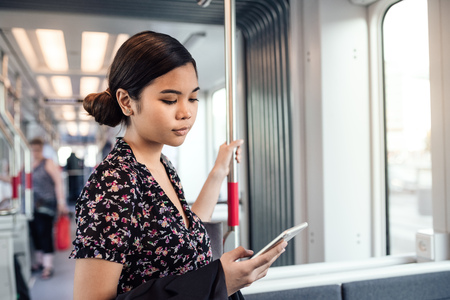 Young Asian student reading texts while riding the trainの写真素材
