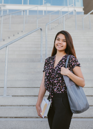 Content young Asian university student standing by campus stairsの写真素材