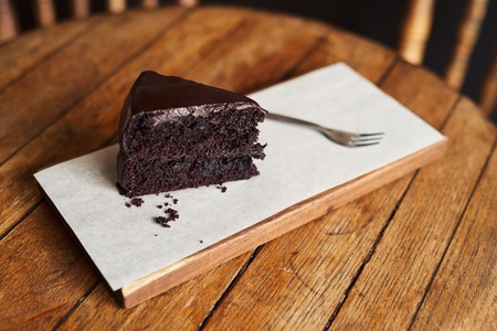 Slice of rich chocolate cake sitting on a cafe tableの写真素材