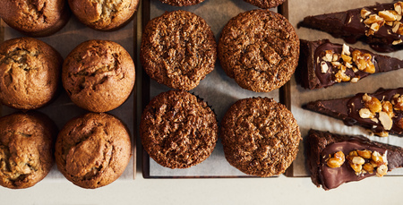 Variety of cakes and muffins sitting on serving boardsの写真素材