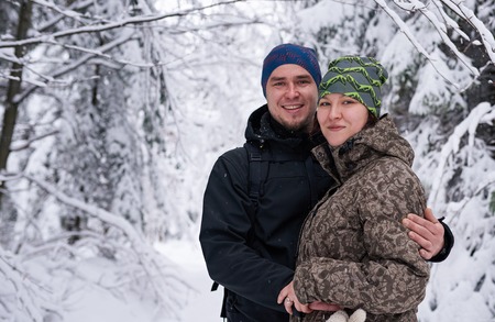 Young couple smiling while hiking in a snow covered forestの写真素材