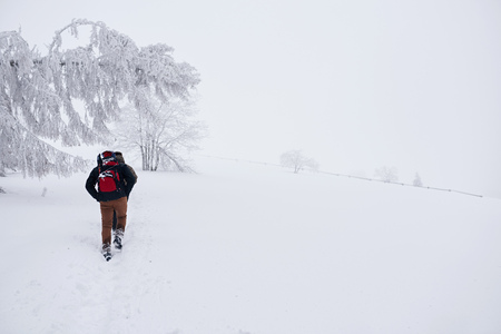 Couple hiking along a snowy trail in the wintertimeの写真素材