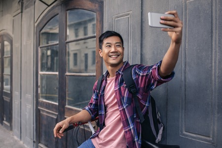 Smiling young Asian man taking a selfie on his bike