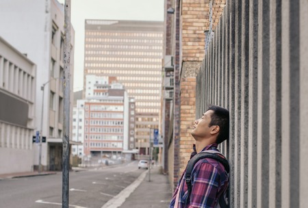 Calm man with eyes closed leaning against a city wallの写真素材