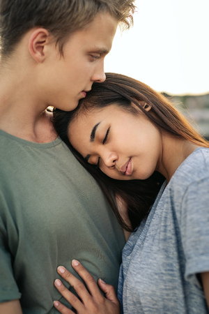 Affectionate young woman hugging her boyfriend by a harborの写真素材