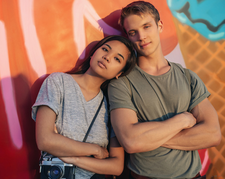 Young couple with attitude standing by a wall of graffitiの写真素材