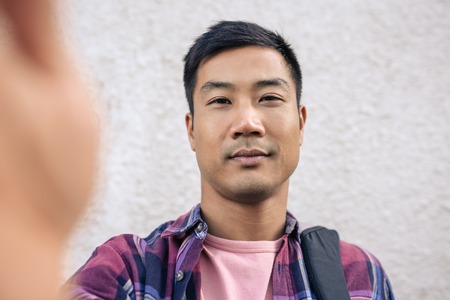 Confident young Asian man taking a selfie outsideの写真素材