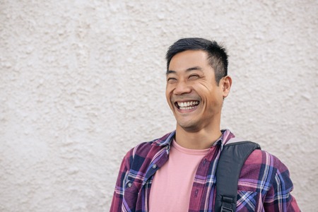 Young Asian man standing on a city street laughingの写真素材