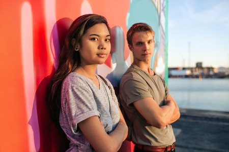 Cool young couple standing by graffiti in the cityの写真素材