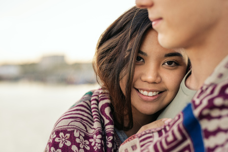 Smiling young woman wrapped in a blanket with her boyfriend