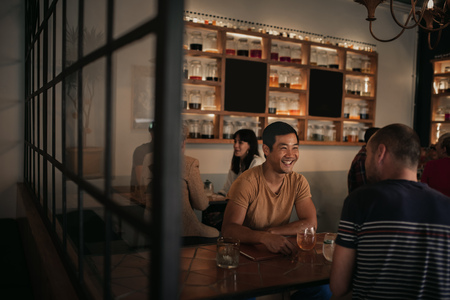 Friends laughing over drinking in a bar together at nightの写真素材