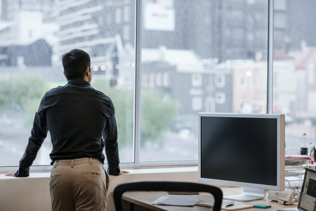 Asian businessman looking at the city through office windowsの写真素材