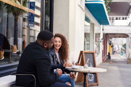 Two smiling friends talking together at a sidewalk cafeの写真素材