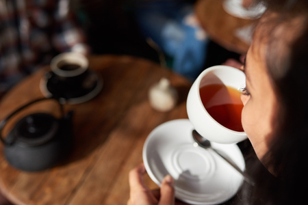 Young woman sitting in a cafe drinking teaの写真素材