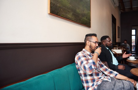 Two men having coffee with friends in a trendy cafeの写真素材
