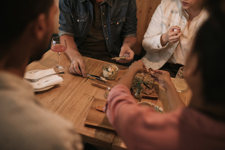 Friends sharing food together in a bar at nightの写真素材