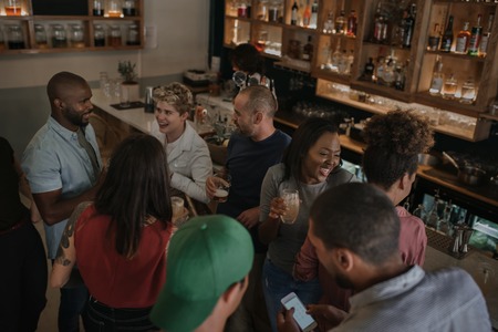 Diverse young friends talking over drinks in a bar