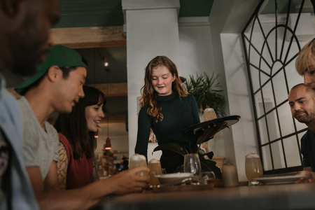 Waitress bringing customers drinks in a bar at night