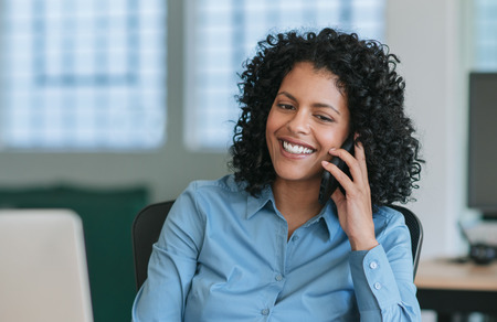 Mature businesswoman sitting at her desk talking on a cellphoneの写真素材