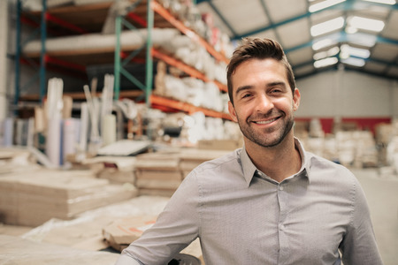 Young manager smiling while standing in a large warehouseの写真素材