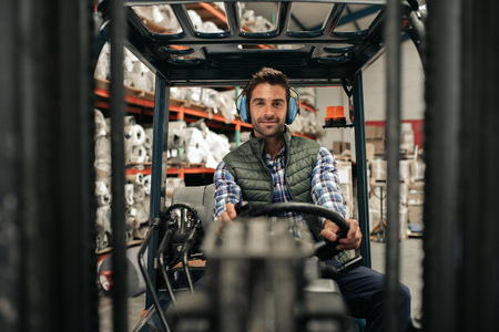 Smiling forklift driver working on the floor of a warehouseの写真素材