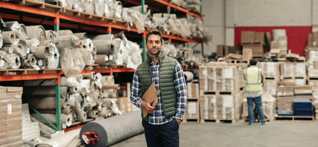 Worker standing with an inventory clipboard on a warehouse floorの写真素材