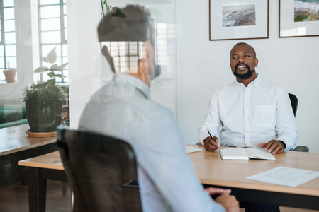 Smiling manager interviewing a potential employee in his office