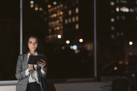 Businesswoman using a tablet in her office in the eveningの写真素材