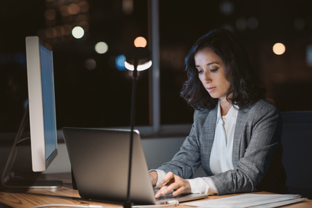 Young businesswoman using a laptop in her office at night