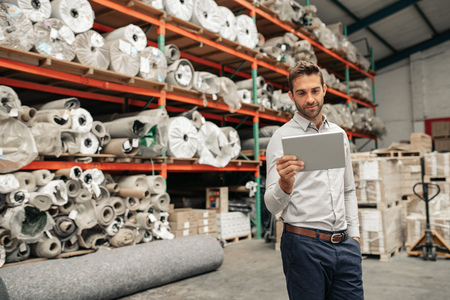 Smiling warehouse manager using a digital tablet while checking stockの写真素材
