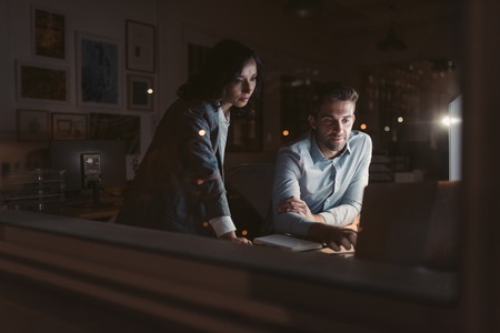 Two young businesspeople working late together in an officeの写真素材