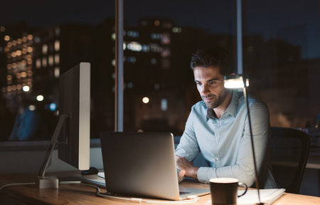 Young businessman working overtime late in the eveningの写真素材