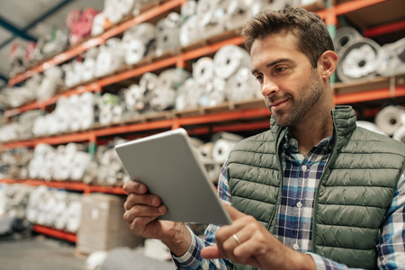 Smiling warehouse worker using a digital tablet to trace stockの写真素材