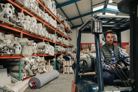 Worker driving a forklift on a warehouse floorの写真素材